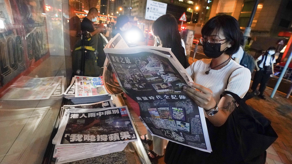 Eine Frau hält die letzte Ausgabe von Apple Daily in der Hand.