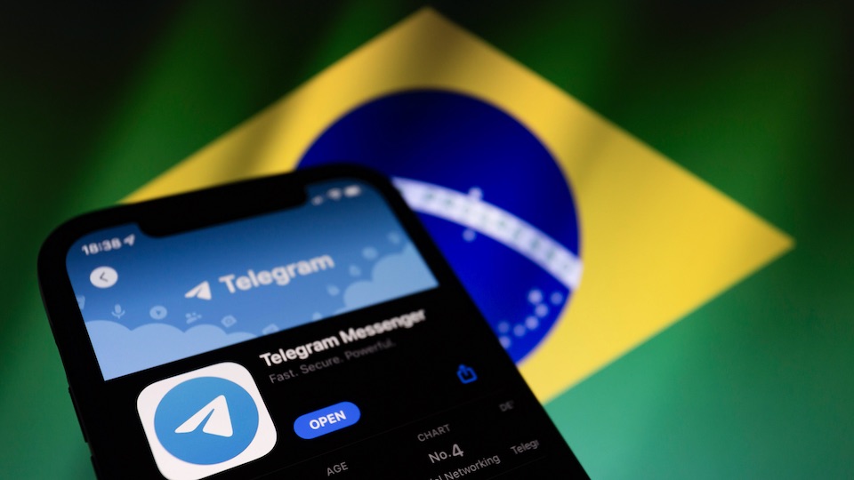 Smartphone mit Telegram im Appstore vor brasilianischer Flagge