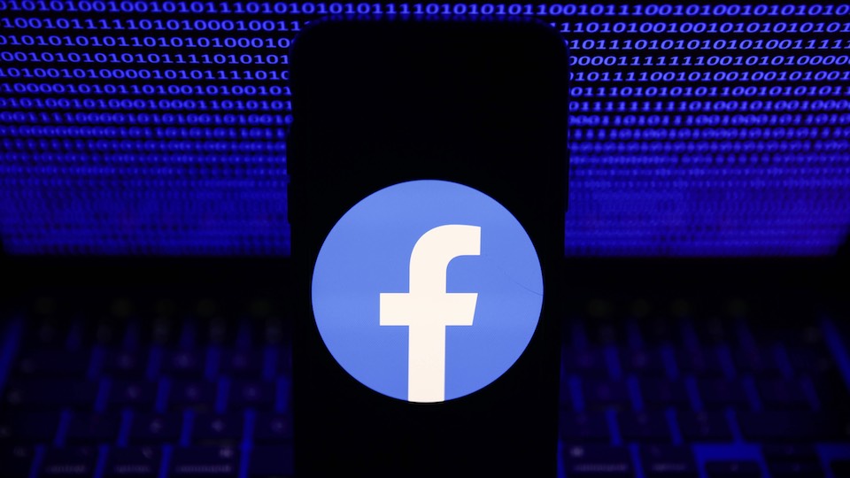 Facebook-Logo auf einem Smartphone vor einem Computer-Bildschirm