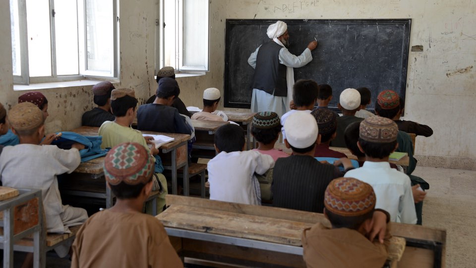 Jungen sitzen in einem Klassenraum mit einem Lehrer vor der Tafel