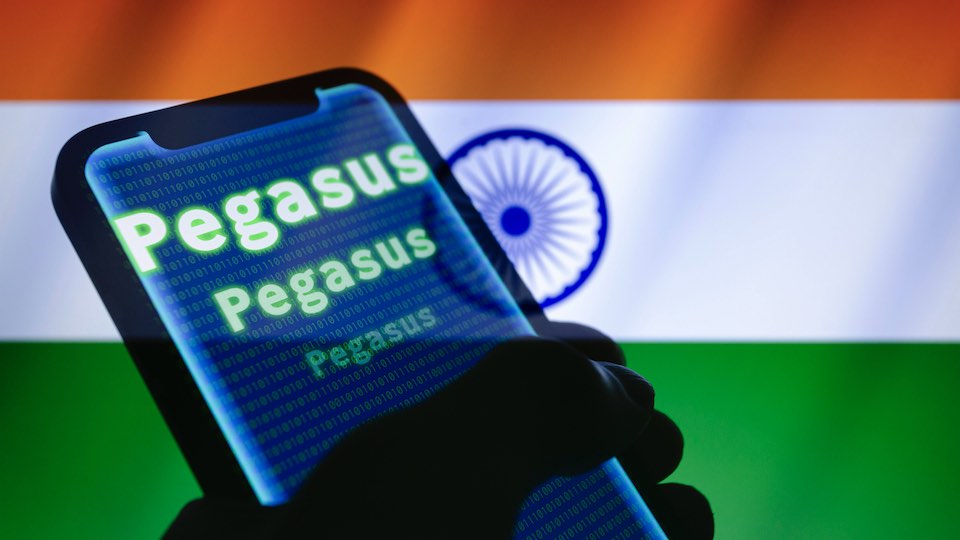 Das Wort Pegasus und Binärcode werden auf einem iPhone angezeigt, im Hintergrund die Flagge Indiens