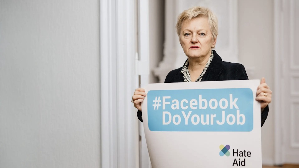 Porträt von Renate Künast mit einem Schild mit der Aufschrift Facebook Do Your Job