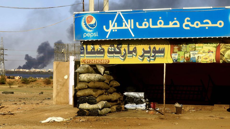 Ein geschlossenes Geschäft in der Stadt Khartoum mit Rauch im Hintergrund